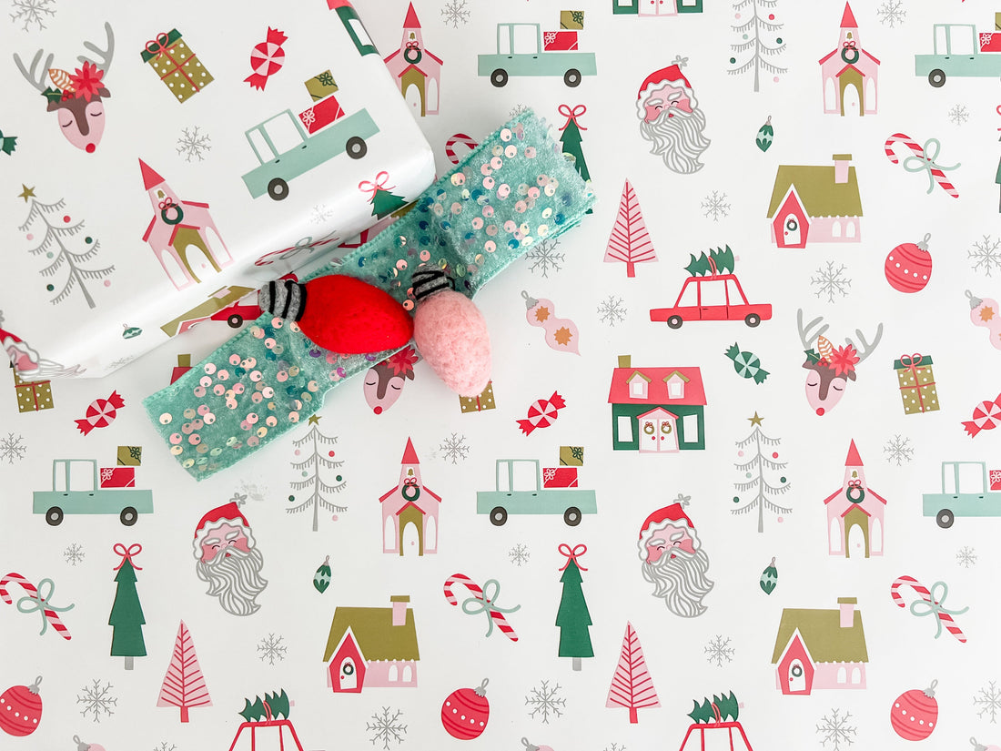 Christmas-themed wrapping paper with reindeer, Santa Claus, and trees on a white background.