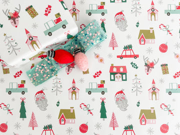 Christmas-themed wrapping paper with reindeer, Santa Claus, and trees on a white background.